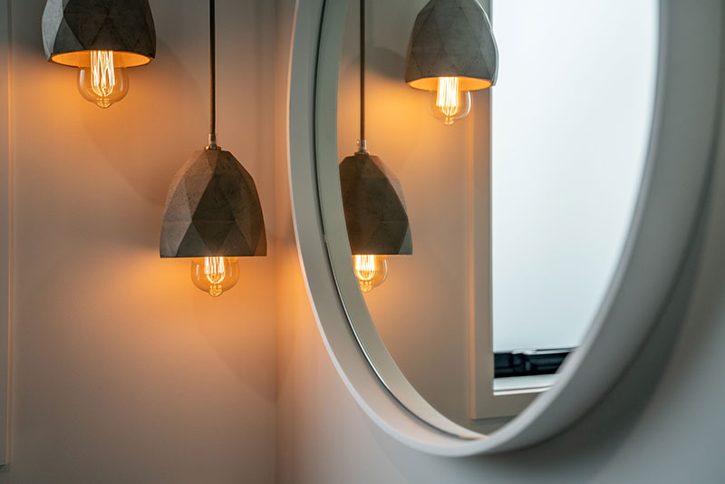 Concrete pendent lights lit up next to white round mirror in Precision Homes Paerata Rise Showhome.