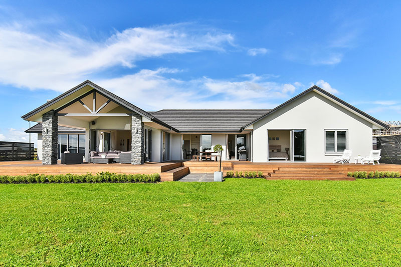 huge wrap around deck on award winning home, plaster with schist pillars