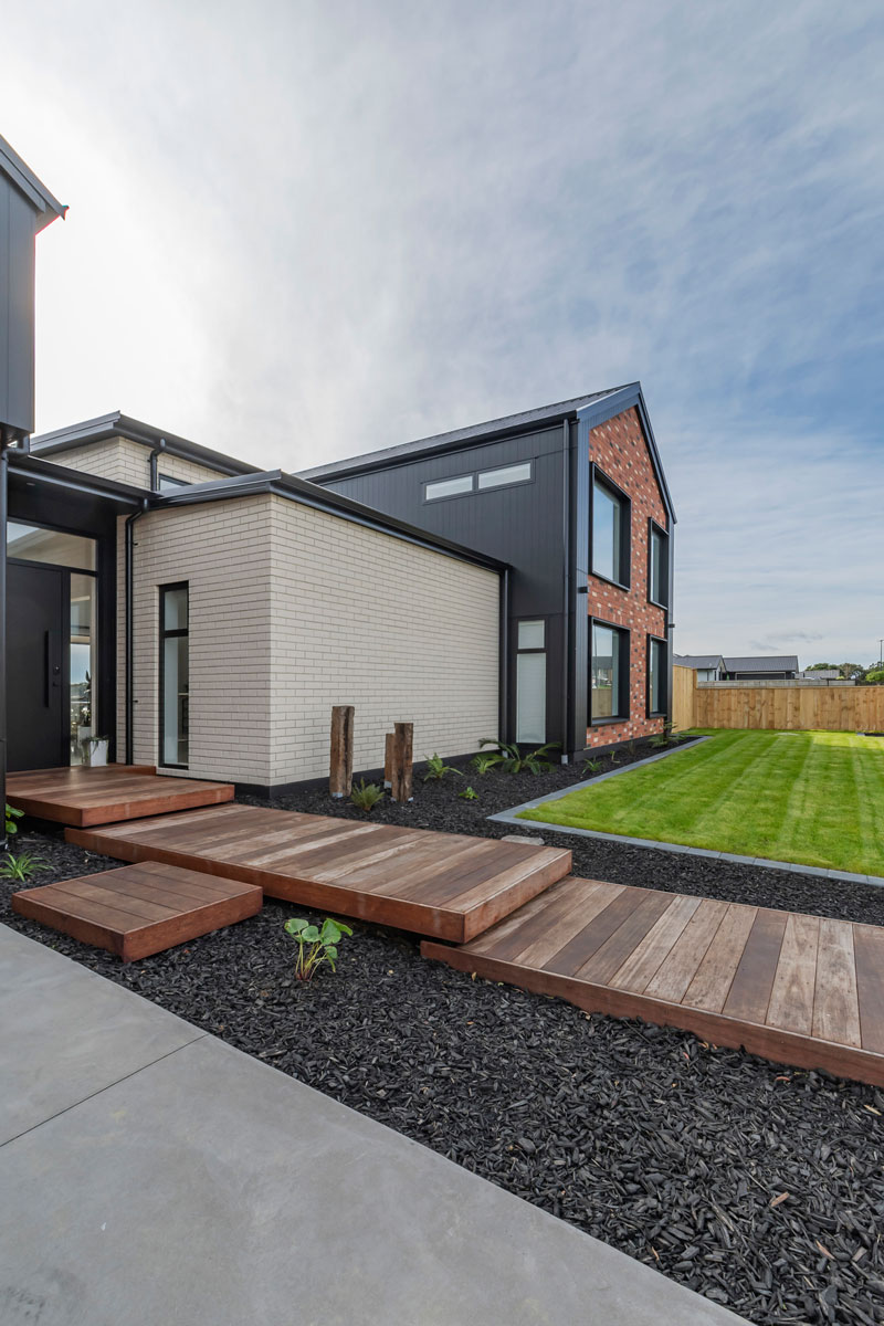 Front of designer home with Black Axon panel, white brick and Red recycled brick features, timber boardwalk