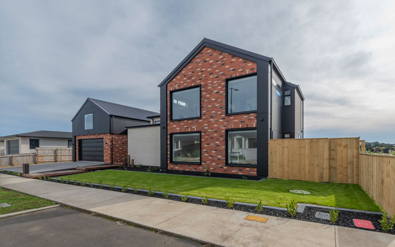 Front of designer home with Black Axon panel, white brick and Red recycled brick features, timber boardwalk