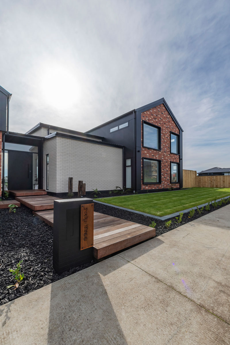 Front of designer home with Black Axon panel, white brick and Red recycled brick features, timber boardwalk