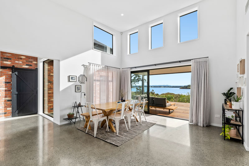 open plan living area with red brick in entrance with polished concrete floors in designer home