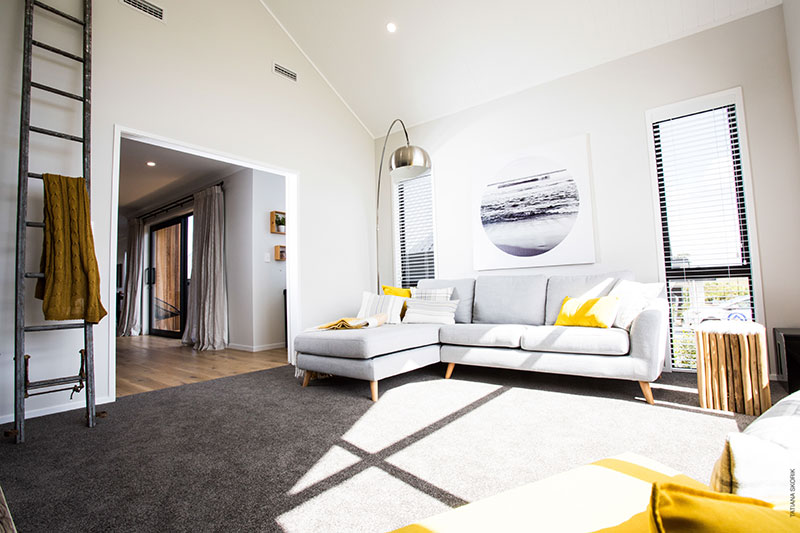 Sun drenched lounge with grey sofa, yellow accents and rustic ladder decor