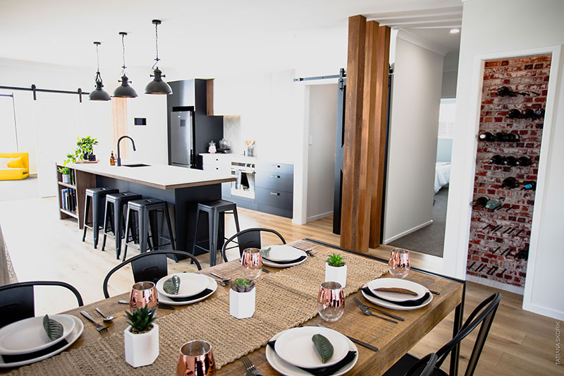 rustic dining and kitchen area with wine cupboard. Cedar posts in black kitchen with barn door