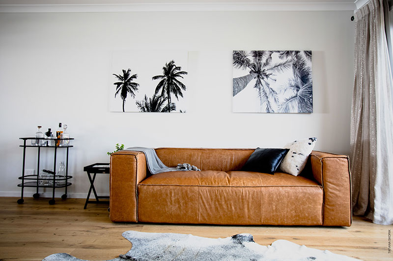 modern leather sofa on timber floor with drinks trolley and cow hide. brown and black accents