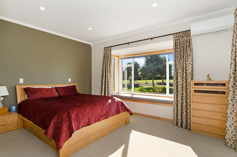 Masterbedroom with olive green feature wall and lovely timber accents in colonial style home