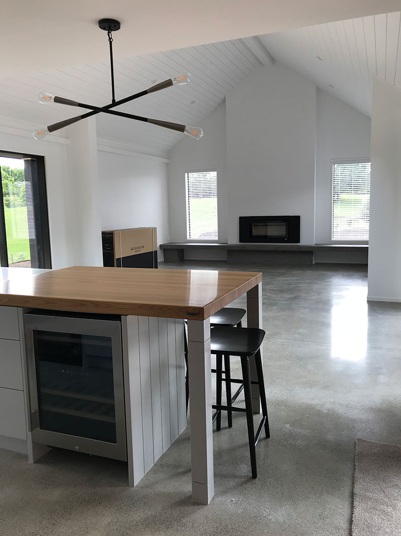 Timber bench, wine fridge and open plan living with polished concrete floor, sarked raking ceilings in hardigroove and fireplace