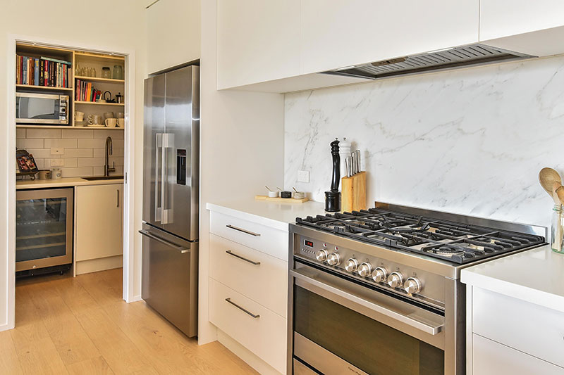 Marble Splashback & large Fisher and Paykel oven in light white kitchen with timber floor and butlers pantry