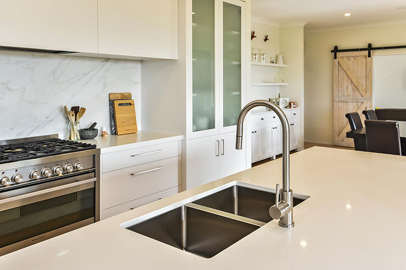 Light, White kitchen with marble splashback, large oven & double sinks. Barn door & built in display cabinets in dining room