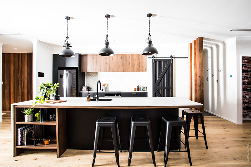 Black and wood kitchen with black industrial pendents, barn door and under bench shelves