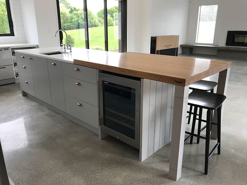 Gorgeous slab of wood used as part of island benchtop with wine fridge underneath. Concrete floor